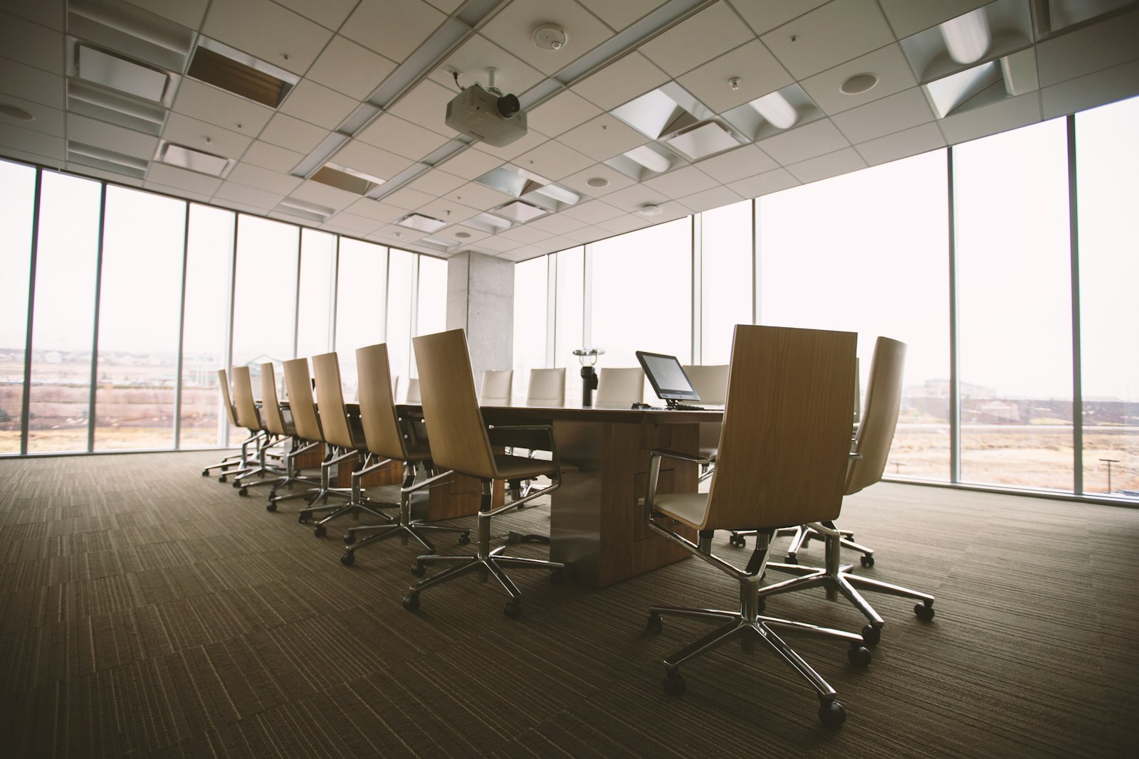 An empty boardroom with a long wooden conference table and tall windows